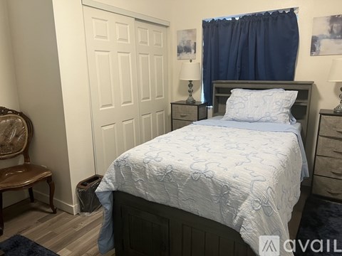 A bedroom with a bed, nightstands, and a chair.