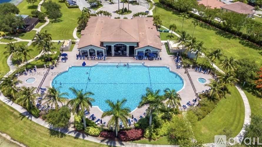 A large swimming pool surrounded by palm trees and a pavilion.