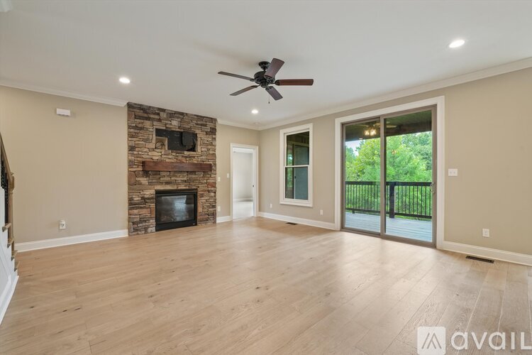 A spacious living room with a stone fireplace and sliding glass doors.