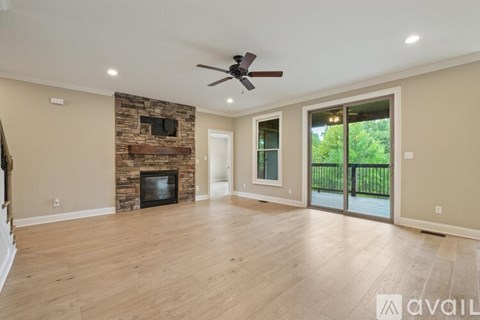 A spacious living room with a stone fireplace and sliding glass doors.