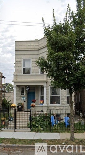 A house with a blue door and a tree in front.