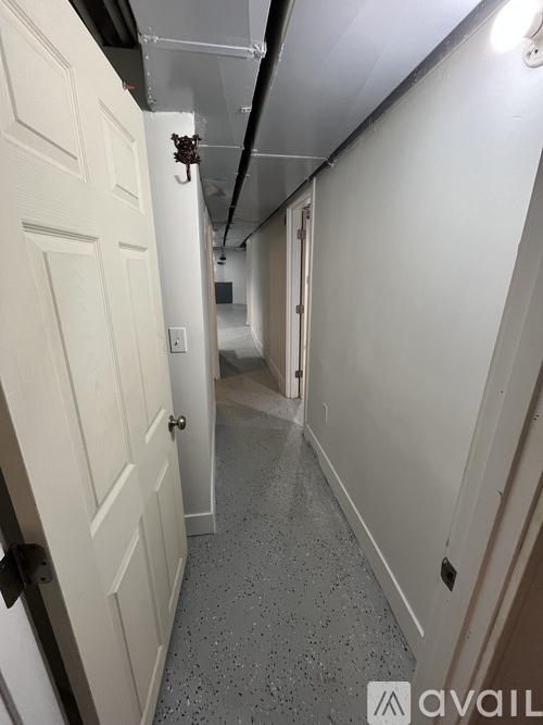 A hallway with a white door and a black handle.