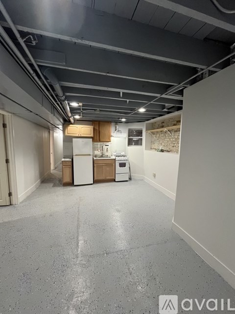 A spacious room with a white refrigerator and a white cabinet.