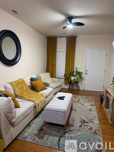 A living room with a white couch and a rug.