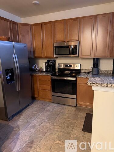 A kitchen with wooden cabinets and a stainless steel refrigerator.