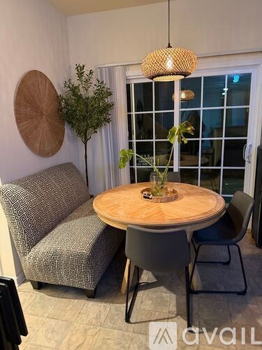 A dining area with a round wooden table, grey chairs, and a potted plant.