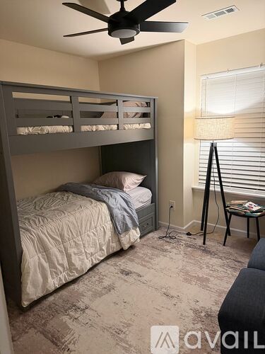 A bedroom with a bed, a chair, and a ceiling fan.