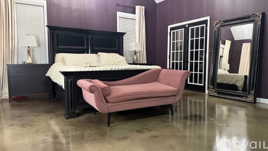 A bedroom with a bed, chair, and mirror.