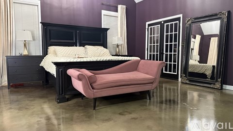A bedroom with a bed, chair, and mirror.