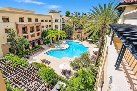 A pool surrounded by palm trees and a patio area.