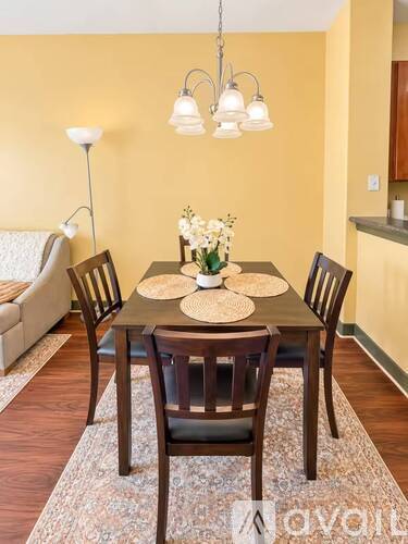 A dining room with a table set for two and a couch in the background.