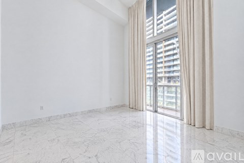 A spacious room with marble flooring and a sliding glass door.
