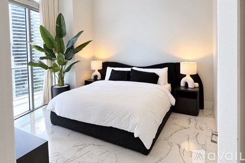 A bedroom with a large bed and a plant in a vase.