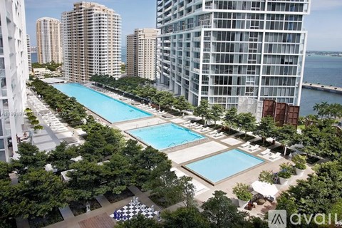 A large swimming pool surrounded by trees and buildings.