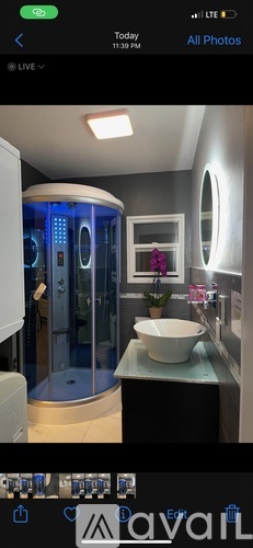 A modern bathroom with a round mirror and a glass shower stall.