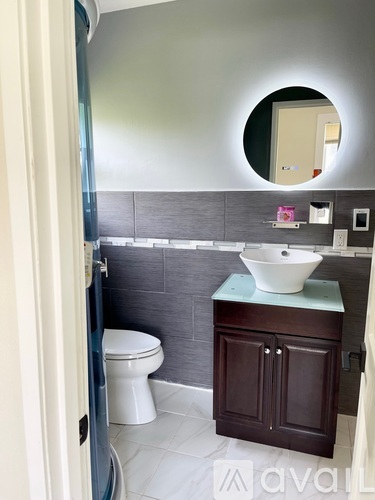 A bathroom with a toilet, sink and mirror.