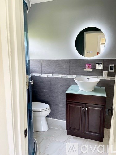 A bathroom with a toilet, sink and mirror.