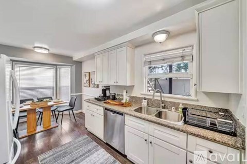 A kitchen with white cabinets and a granite countertop.