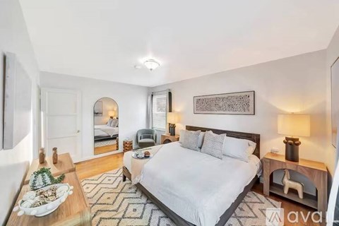 A well-lit bedroom with a large bed and a wooden bench.
