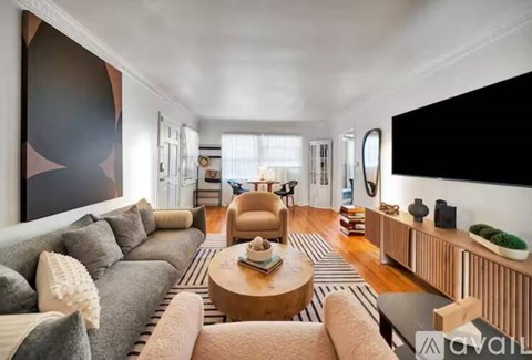 A living room with a grey sofa, a wooden coffee table, and a large painting on the wall.