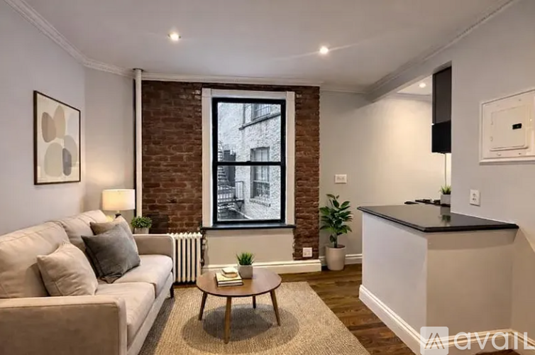 A living room with a white couch, a coffee table, and a brick wall.