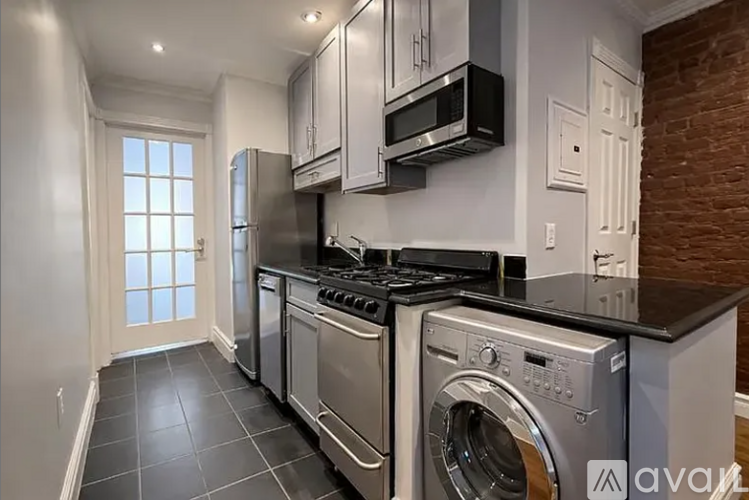A modern kitchen with stainless steel appliances and a black countertop.