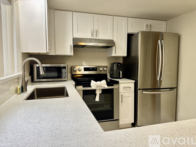 A kitchen with a refrigerator, microwave, oven, and sink.