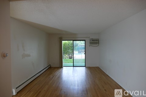 A room with wooden floors and a window showing greenery outside.