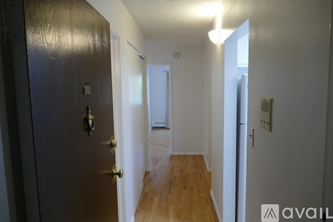A hallway with a wooden floor and white walls.