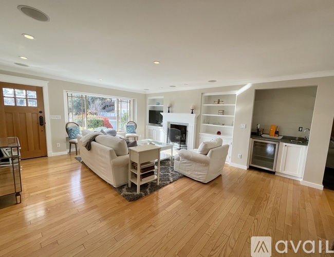 A spacious living room with a white sofa set and a fireplace.