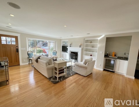 A spacious living room with a white sofa set and a fireplace.