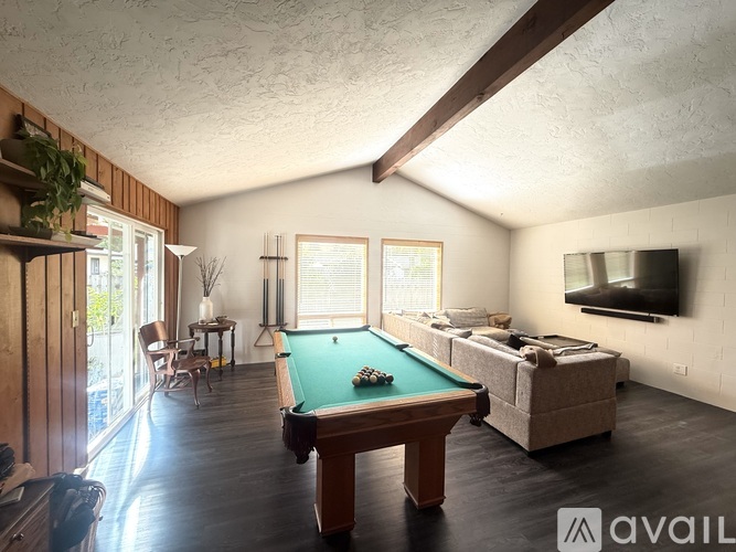 A pool table is in the middle of a room with a couch and a television.