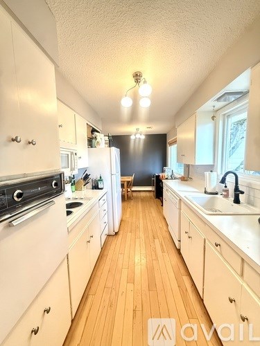 A kitchen with white appliances and wooden floors.