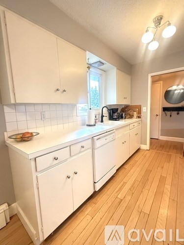 A kitchen with white cabinets and a wooden floor.