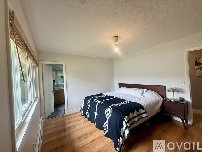 A bedroom with a bed, nightstand, and window.