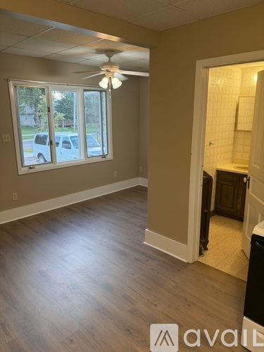 A room with a ceiling fan and a window overlooking a street.