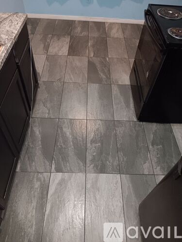 A kitchen with a tile floor and a black dishwasher.