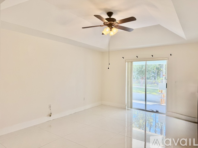 A spacious room with a ceiling fan and sliding glass doors.