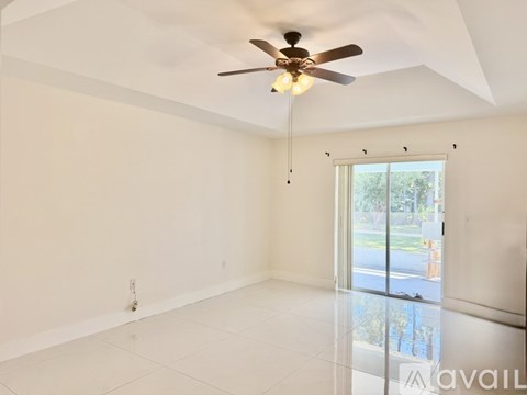 A spacious room with a ceiling fan and sliding glass doors.