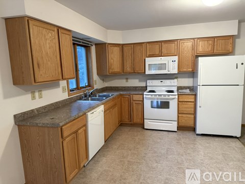A kitchen with wooden cabinets and white appliances.