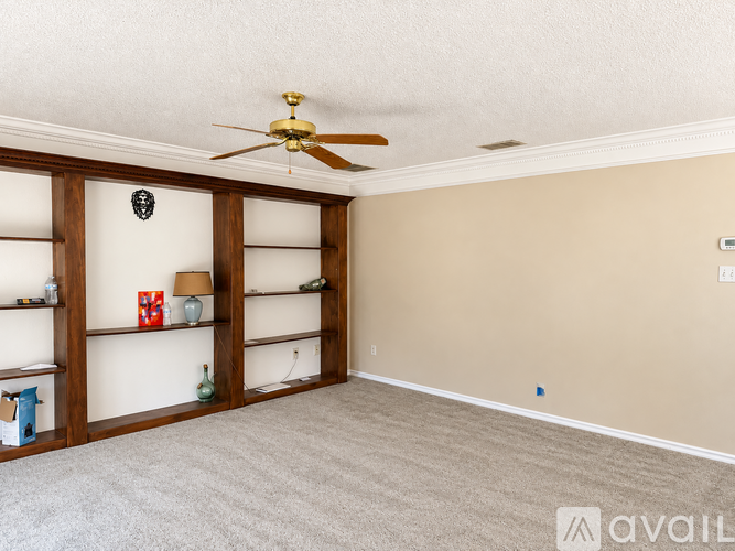 A room with a ceiling fan and shelves.