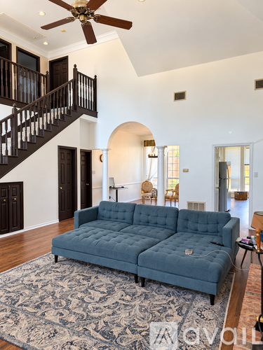 A living room with a blue couch and a fan on the ceiling.