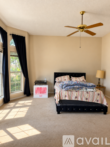 A bedroom with a bed, nightstand, and window with curtains.
