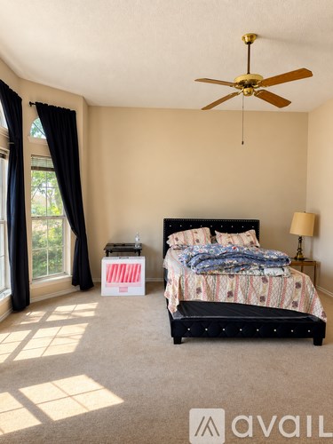 A bedroom with a bed, nightstand, and window with curtains.