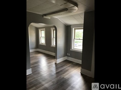 A room with wooden floors and two windows.