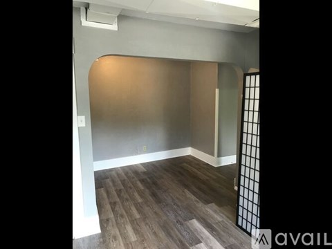 A room with wooden flooring and a wall with a window.