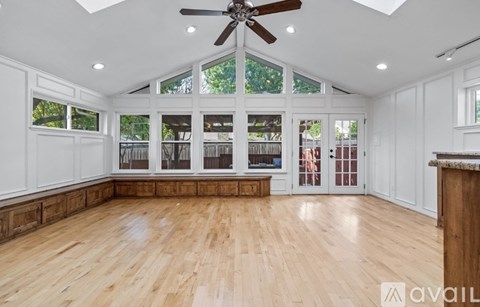 A spacious room with wooden floors and a ceiling fan.
