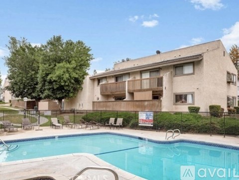 A swimming pool in front of a building with a sign that says "available".
