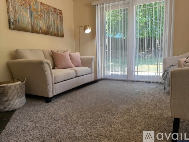 A living room with a beige couch and a painting on the wall.