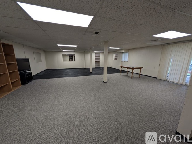 A spacious office room with a carpeted floor and a television on the left side.